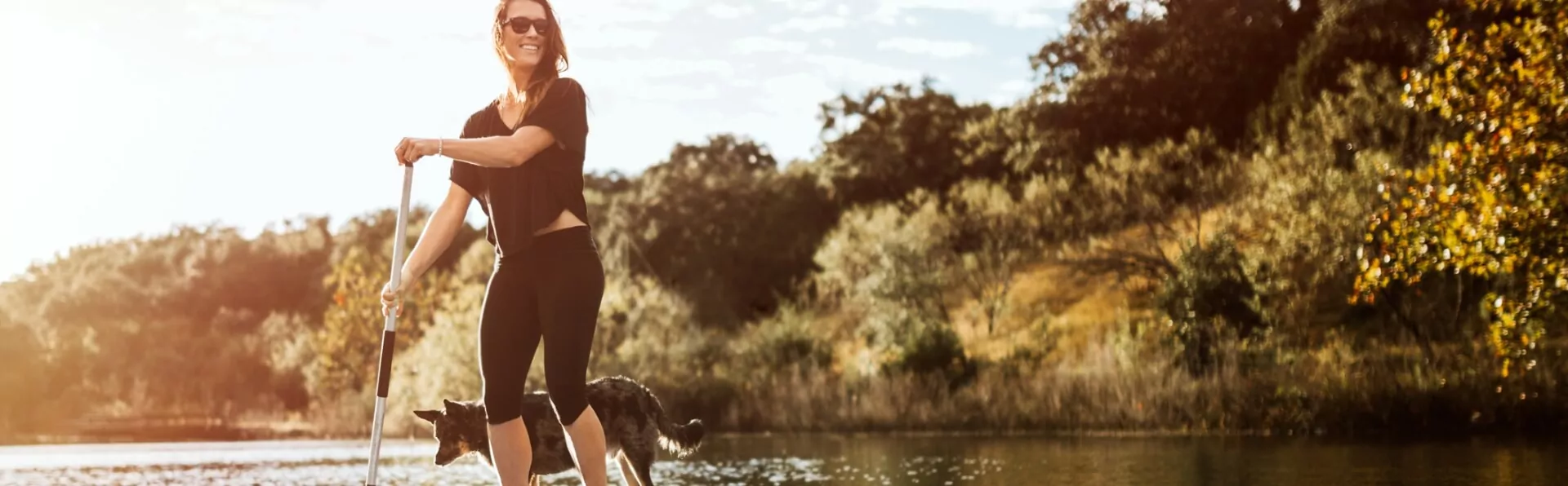 A picture of a young woman doing paddle boarding with her dog in the lake of Waxahachie